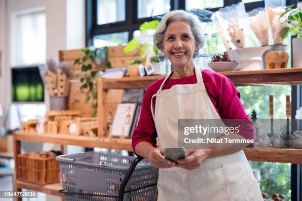 hiring senior experienced employees can help your business. portrait of a senior asian small business employee working in a home decor store while standing in front of the products shelf cabinet. - personalized medicine stock pictures, royalty-free photos & images