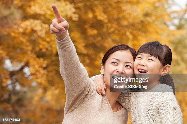 mother and daughter enjoying a park in autumn - tochter zeigt stock-fotos und bilder