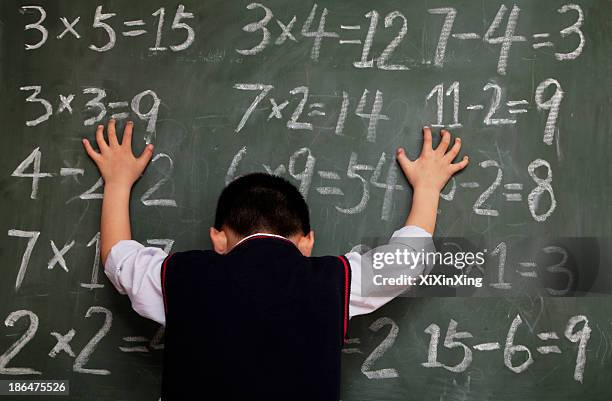 schoolboy in front of blackboard with hands on chalkboard - symbole mathématique photos et images de collection