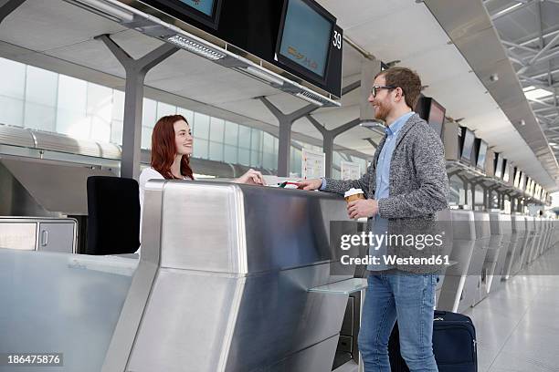 germany, cologne, young woman giving ticket to mid adult man - flughafen check-in stock-fotos und bilder