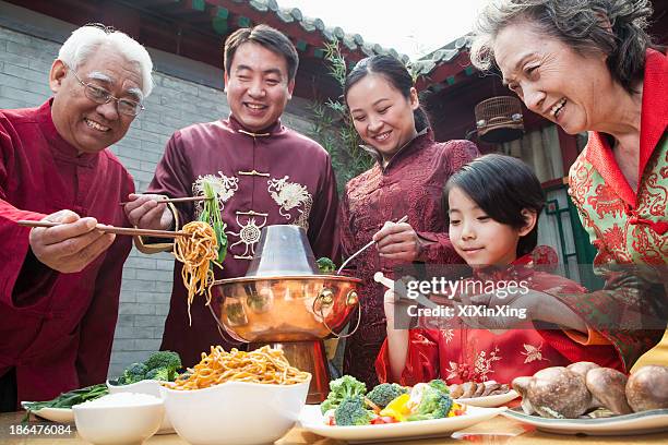 family enjoying chinese meal in traditional chinese clothing - chinese family eating stock pictures, royalty-free photos & images