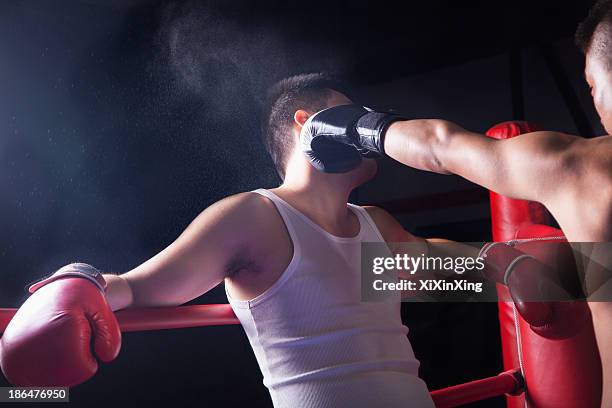 over the shoulder view of male boxer throwing a knockout punch in the boxing ring - knockout punch stock pictures, royalty-free photos & images