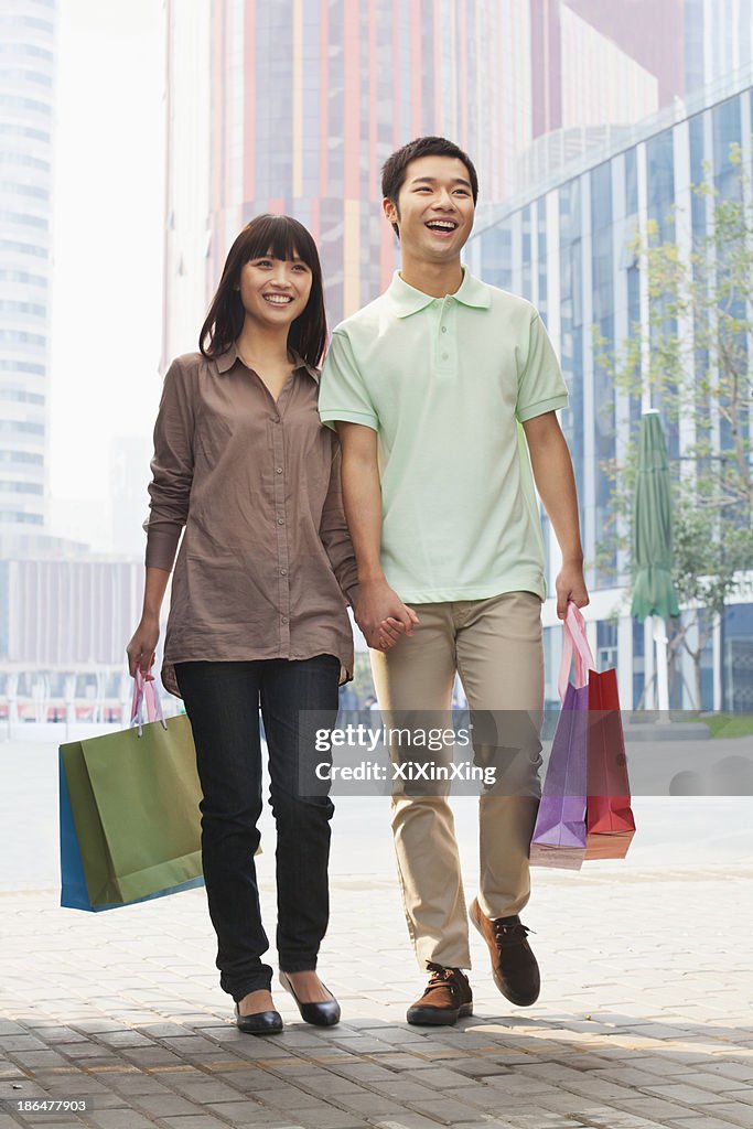 Young couple walking with shopping bags in hands, Beijing, China