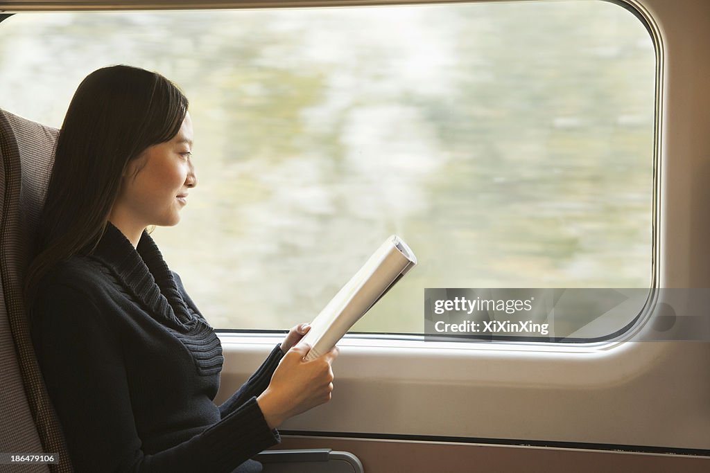 Young Woman Reading a Magazine While Riding the Train