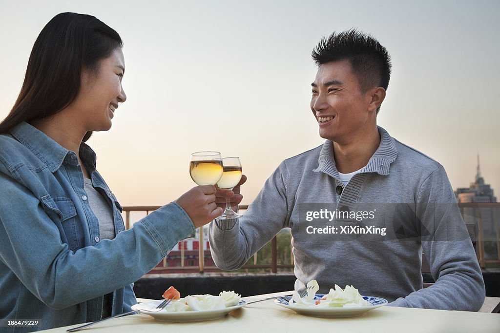 Young couple eating on the roof top, toast
