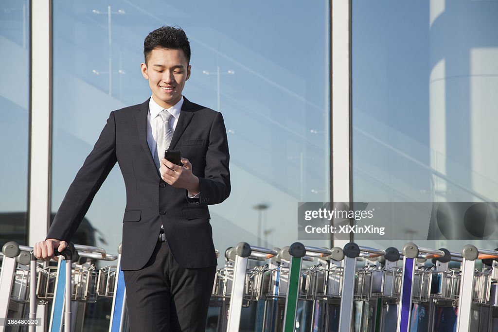 Traveler looking at cellphone next to row of luggage carts