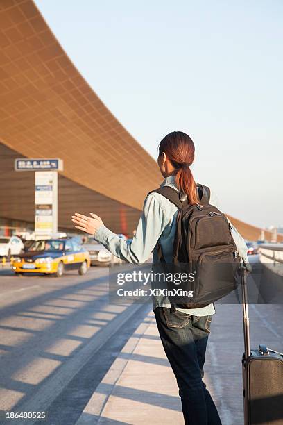 young traveler hailing a taxi at airport - hail stock pictures, royalty-free photos & images