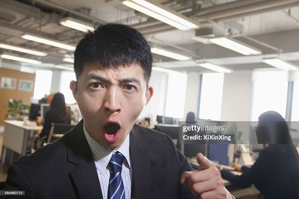 Young Businessman pointing and shouting, looking at camera