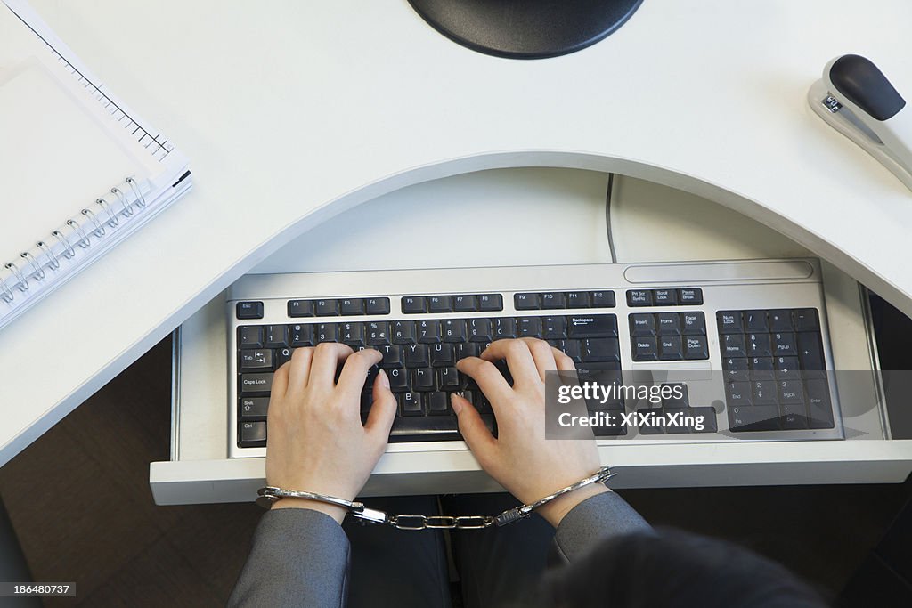 Young businesswoman handcuffed to her office chair, directly above