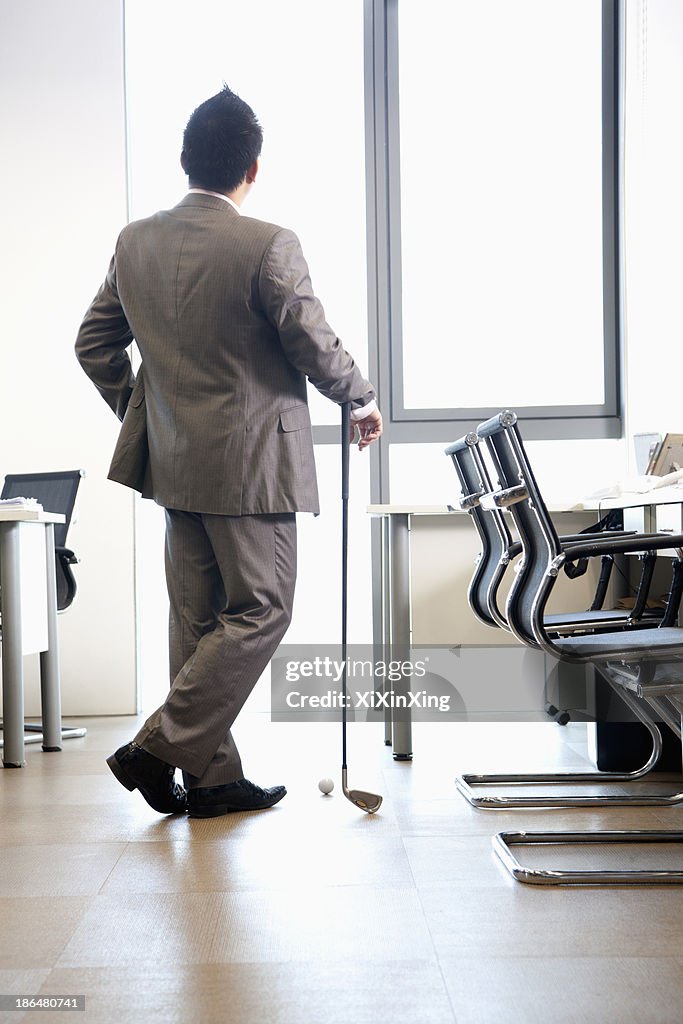 Businessman holding golf club in his office