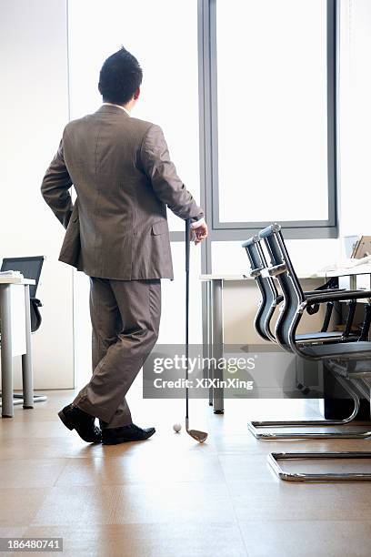 Businessman Holding Golf Club In His Office, Foto de stock