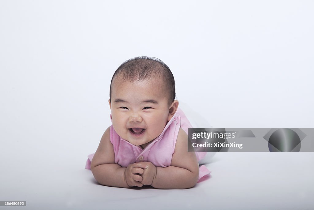 Portrait of smiling and laughing baby lying down, studio shot, white background