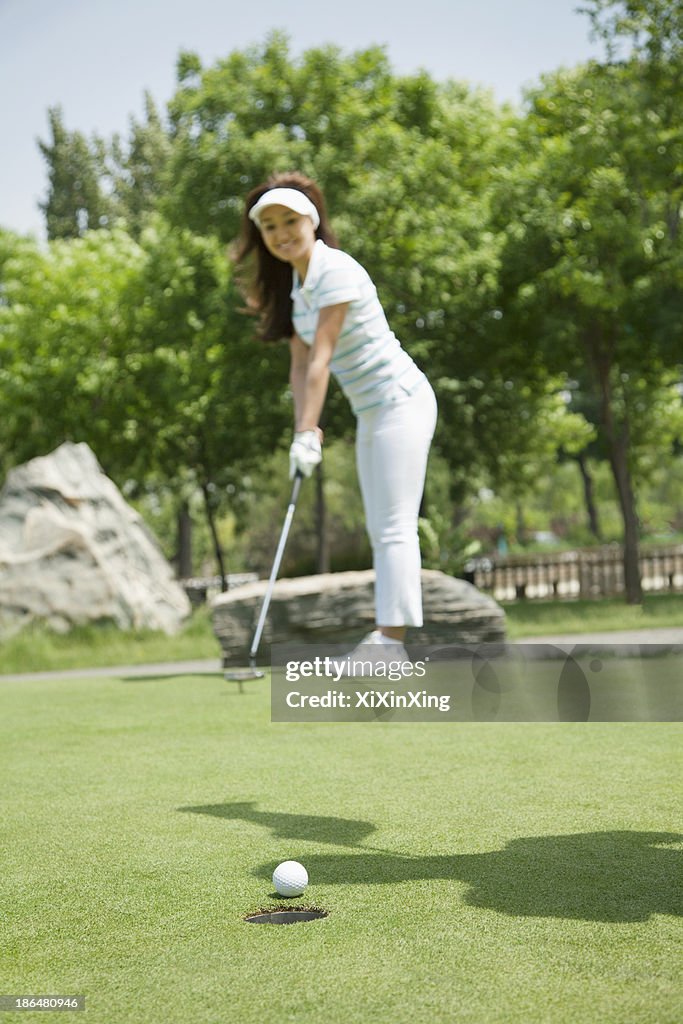 Young woman hitting the ball on the golf course