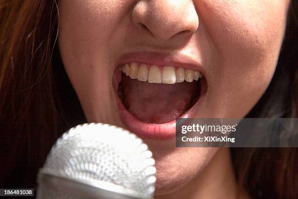close-up of young woman singing into a microphone at karaoke - microphone mouth stock-fotos und bilder