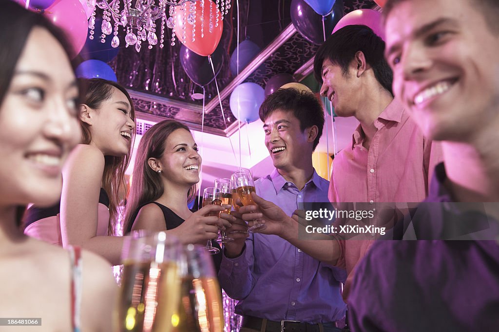 Group of friends celebrating, toasting with champagne, nightclub in Beijing