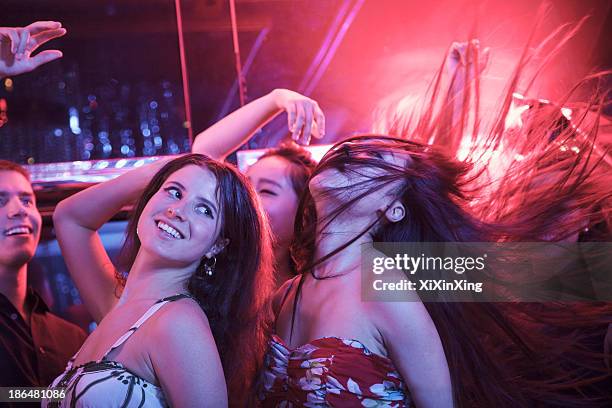 multi-ethnic group of friends with hands in the air dancing among balloons in a nightclub, hair toss - haare schütteln stock-fotos und bilder