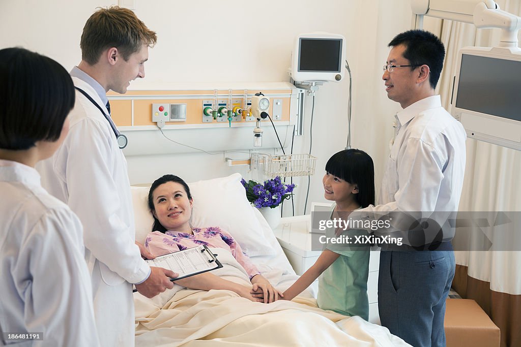 Family visiting the mother in the hospital, discussing with the doctor