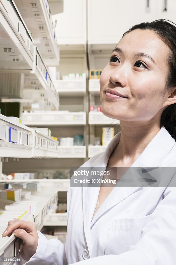 Pharmacist looking for medication on a shelf in a pharmacy