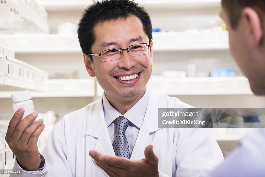 Smiling pharmacist showing prescription medication to a customer