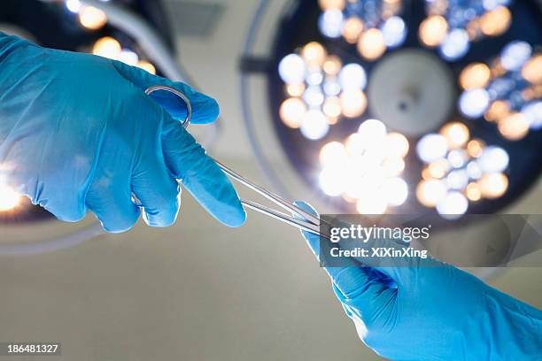 close-up of gloved hands passing the surgical scissors, operating room, hospital - cirugia fotografías e imágenes de stock