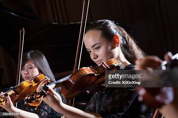 violinists playing during a performance, head and shoulders - violinist foto e immagini stock