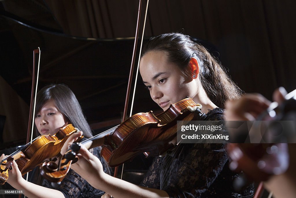 Violinists playing during a performance, head and shoulders