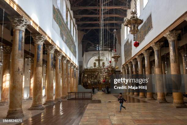 Palestinian boy runs in Church of Nativity on December 18, 2023 in Bethlehem, West Bank. Last month, Christian Palestinian leaders here called off...