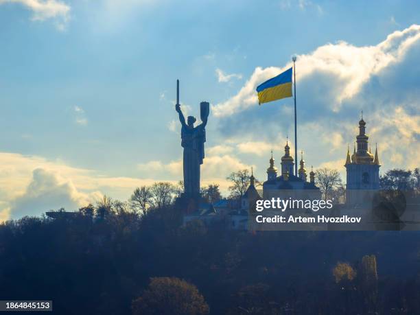 motherland mother monument and huge ukrainian flag on kyiv hill - kiew stock-fotos und bilder