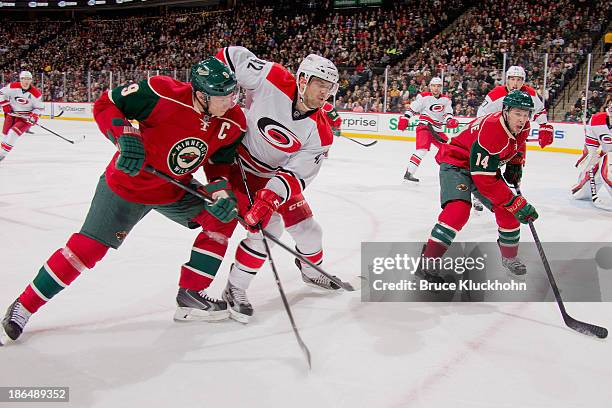 Mikko Koivu and Justin Fontaine of the Minnesota Wild battle for a loose puck with Brett Sutter of the Carolina Hurricanes during the game on October...