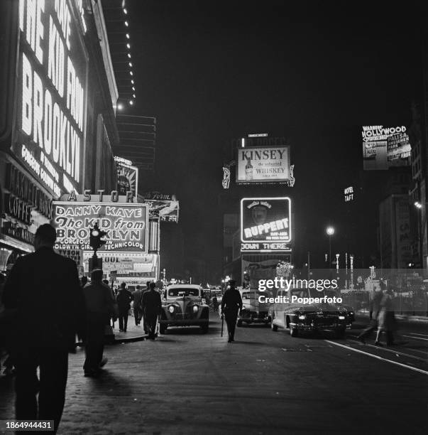 Busy night time view at 3am of pedestrians passing cars and taxis outside the Astor Theatre at 1537 Broadway at the intersection with West 45th...