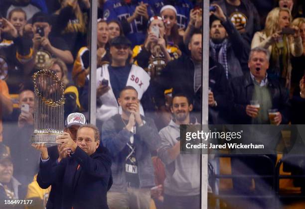 President and Chief Exective Officer Larry Lucchino of the Boston Red Sox raises the World Series trophy at TD Garden during the game between the...