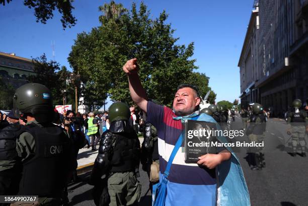 Demonstrator holding an image of Eva Peron shouts slogans as police officers stand guard during a demonstration against President Javier Milei and...