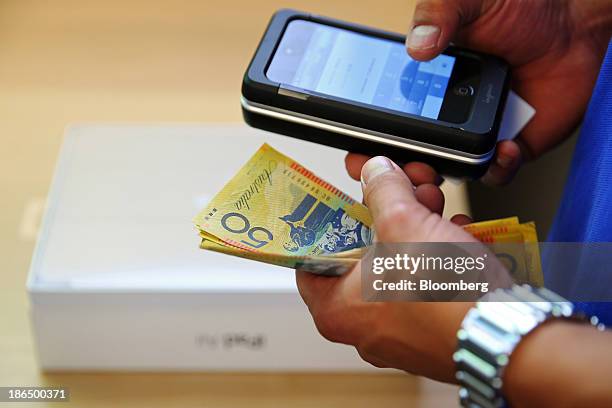 An Apple Inc. Employee holds Australian dollar banknotes as a new iPad Air is purchased at the company's George Street store in Sydney, Australia, on...