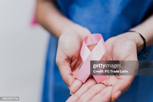 nahaufnahme einer patientin, die im krankenhaus ein brustkrebsband in der hand hält - vorbeugung stock-fotos und bilder