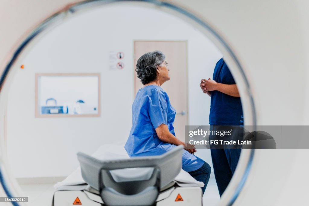 Senior woman talking to a nurse on a MRI tomography at hospital