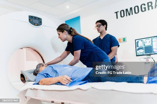 krankenschwester spricht, während sie patientin auf eine tomographie-untersuchung im krankenhaus vorbereitet - magnetresonanztomograph stock-fotos und bilder