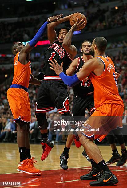 Derrick Rose of the Chicago Bulls leaps to pass between Tim Hardaway Jr. #5 and Tyson Chandler of the New York Knicks at the United Center on October...