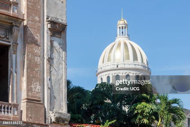 Havana, Cuba, The gold colored dome of the Capitolio building is contrasted with a weathered apartment building.
