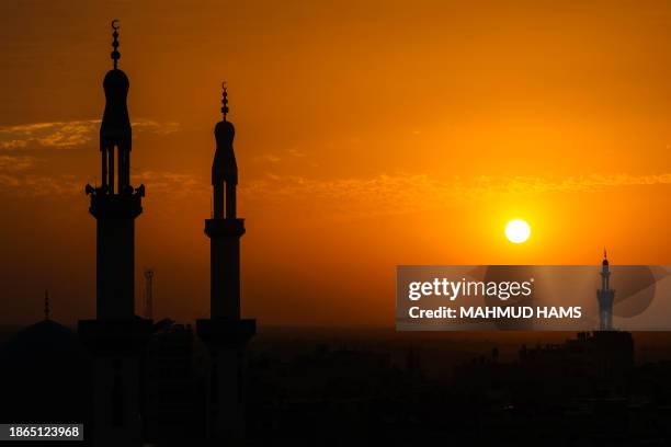 Minarets are silhouetted in front of the setting sun in Rafah, on the southern Gaza Strip on December 21 amid continuing battles between Israel and...