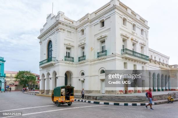Santa Clara, Cuba, A tricycle drives by the colonial Charity Theater or Teatro La Caridad. The landmark building is a National Monument and a famous...