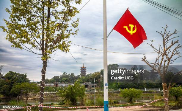 Vietnamese communist party hammer and sickle flag next to the Ka Long river looking across the border towards a Buddhist pagoda in Dongxing in China.