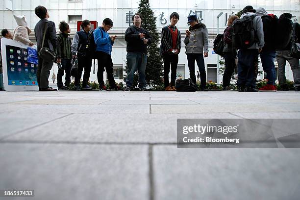 Customers wait in line outside an Apple Inc. Store ahead of the launch of the company's iPad Air in the Ginza district of Tokyo, Japan, on Friday,...