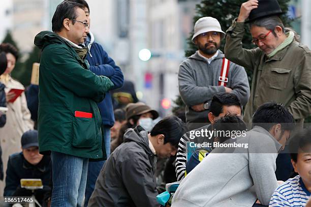 Customers wait in line outside an Apple Inc. Store ahead of the launch of the company's iPad Air in the Ginza district of Tokyo, Japan, on Friday,...