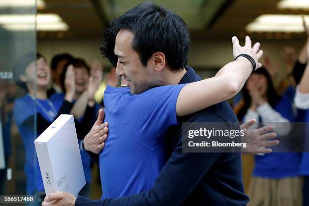 An employee, left, hugs the first customer to purchase the Apple Inc. IPad Air at the company's store in the Ginza district of Tokyo, Japan, on...