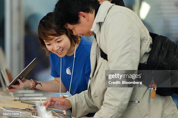 An employee, left, speaks to a customer as he tries out an Apple Inc. IPad Air at the company's store in the Ginza district of Tokyo, Japan, on...