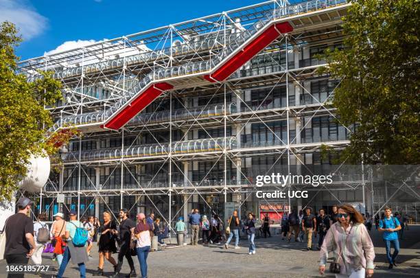 People walk in the Place Georges Pompidou next to the modernist Pompidou Centre in Paris, France.