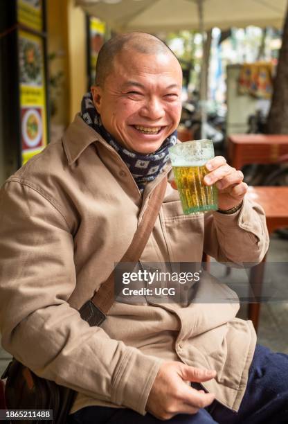 Vietnamese man drinks a glass of bia hoi on the street in Hanoi, Vietnam. Bia Hoi, or fresh beer, is a popular and cheap drink that is especially...