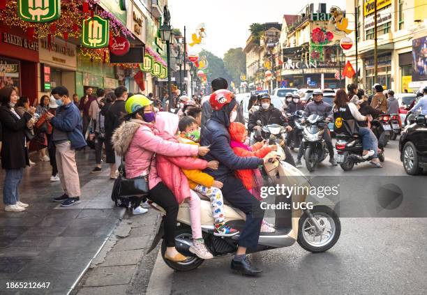 Vietnamese couple and their three young children crammed onto a scooter in heavy traffic in central Hanoi, Vietnam.