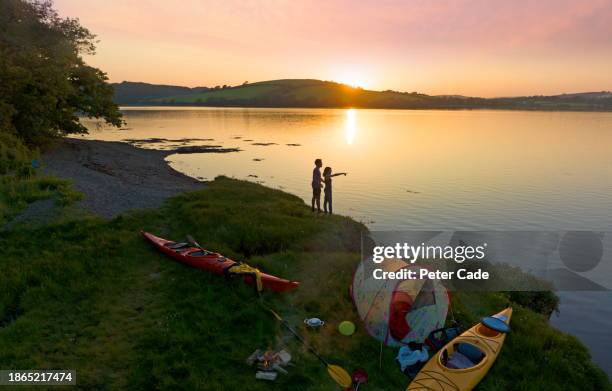 couple on camping trip next to lake at sunset - beautiful man sunlight stock pictures, royalty-free photos & images