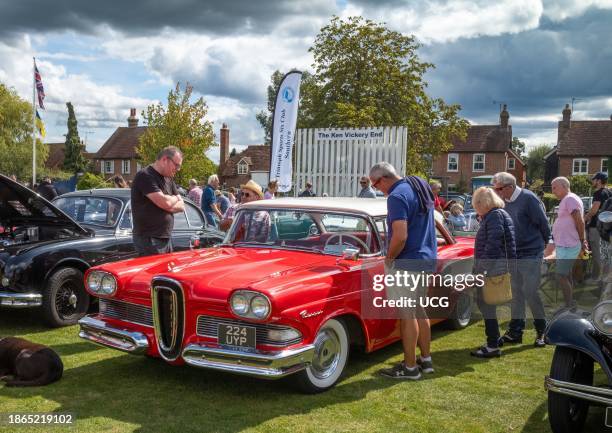 People stop to look at a bright red 1958 Ford Edsel car from the USA at Wisborough Green Village Fete, West Sussex, UK. The car, when it was...